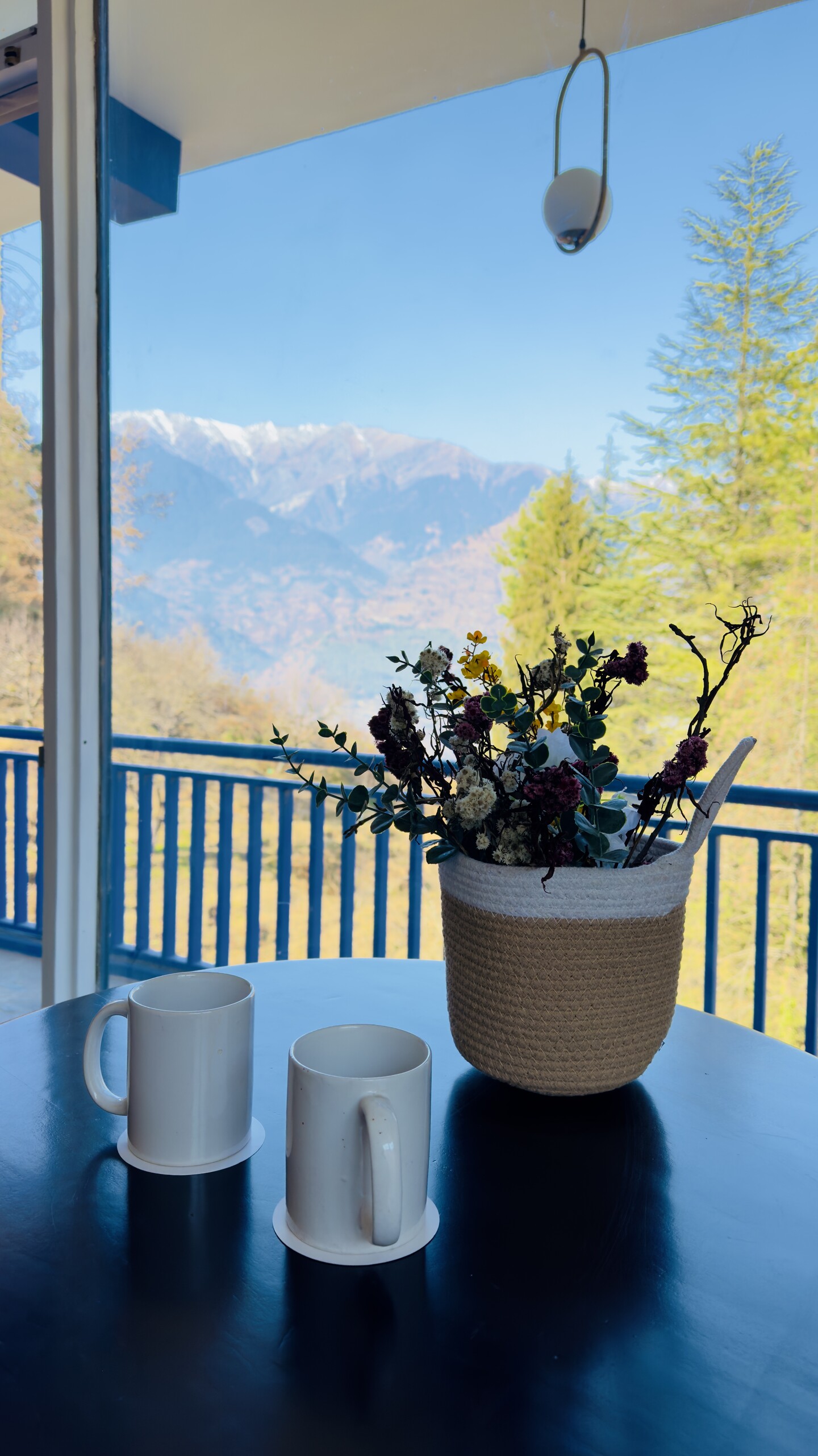 Two coffee mugs on balcony table with Himalayan view