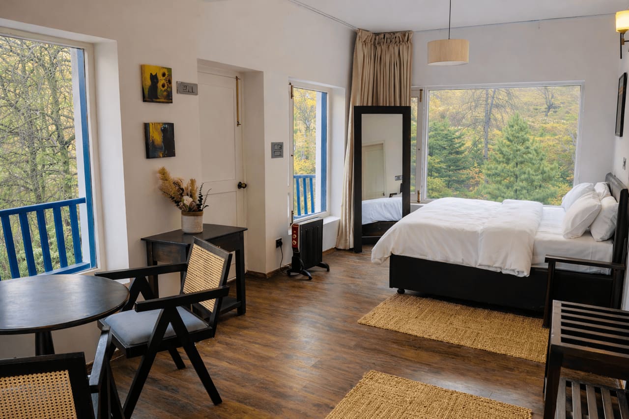Writer's Room with a bed, a table and two cane chairs and large windows onto the forest